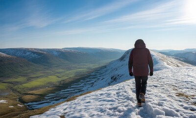 Fototapeta premium Person hiking on snowy mountain ridge, vast valley view