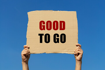 Good to go text on cardboard paper holding by a woman's hand with blue sky background