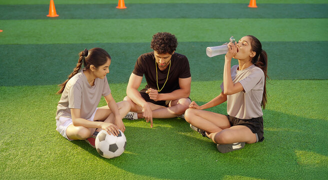 Indian young adult gen z woman lady talk casual gossip fit man coach guy take day time break area place male speak give game advice to teen sports female girl player hold bottle drink water