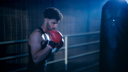 Indian young adult gen z angry fit boxer man guy wear gloves do hand fist boxing punch beat on bag...