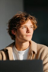 Thoughtful young man gazes into distance, illuminated by soft na