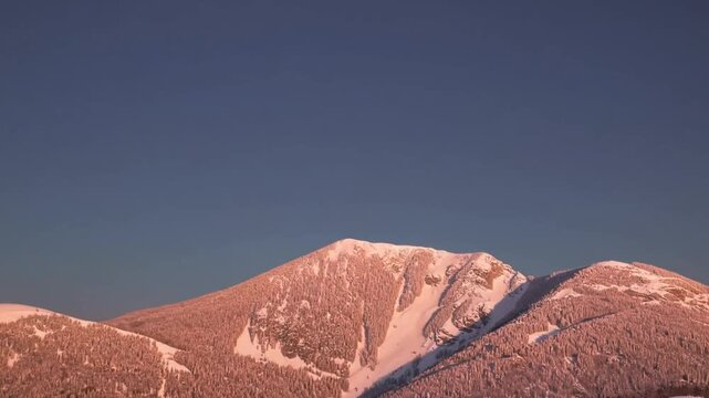 Beautiful Sunrise Over Snow-Capped Mountain Peak with the Moon Still Visible in the Morning Sky