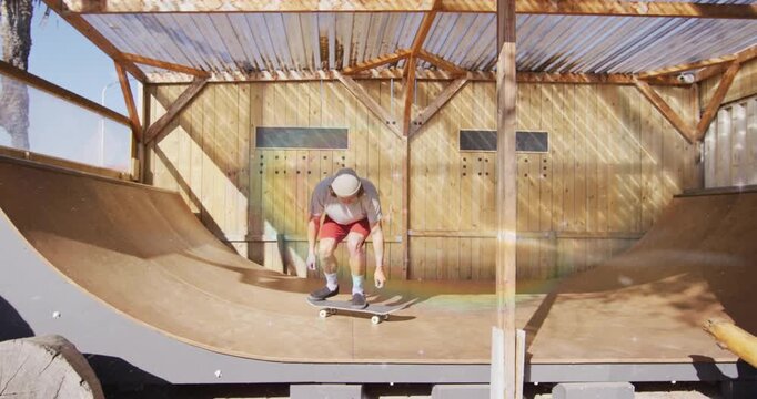 Male skateboarder pushing off wooden halfpipe and ollieing under sunlight while practicing trick
