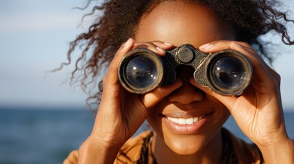 African American Woman on Beach Looking Through Binoculars with Cheerful Expression