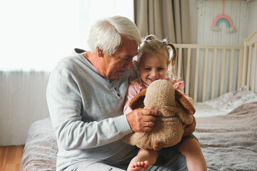 Grandfather and little baby girl grandchild playing colorful toys blocks. Caring granddad having...
