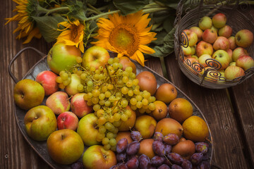 Schale mit Obst, Äpfel, Birnen, Weintrauben und Pflaumen und Sonnenblumen