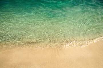 Serene Beach Shoreline. Clear turquoise water gently laps against a sandy beach.