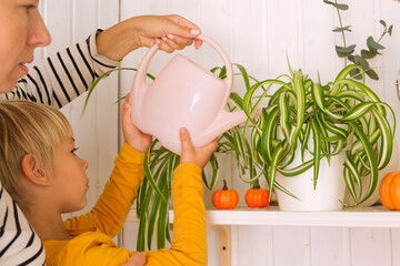 Mother with Children Enthusiastically Learning to Watering Plants, Care in a Bright Home Environment. Kids nurture a houseplants which fosters a sense of love and responsibility. Mom, son and daughter