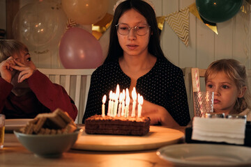 Teenager Child Celebrating Birthday Party at Home. Cheerful Girl's Birthday Celebration. Teen kid female blowing candles on festive cake. Surprise teen sister congratulate children birth