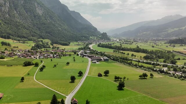 Aerial Drone View of Green Valley with Villages, Roads, and Mountains in the Swiss Alps near Flums and Walenstadt, St. Gallen, Switzerland