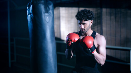Indian young adult gen z angry fit boxer man guy wear gloves do hand fist boxing punch beat hit on...