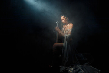 art photo real person fantasy woman queen eyes closed praying hands folded in prayer holding sword...