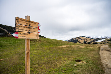 Seiser Alm, South Tyrol - Wooden direction sign reading "Puflatsch-Umrundung" and "Arnikah?tte" in front of the mountain panorama of the Italian Dolomites.