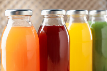 Tasty juices in glass bottles on blurred background, closeup