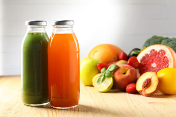 Tasty juices in glass bottles, fresh ingredients and basil on wooden table against light grey background, closeup