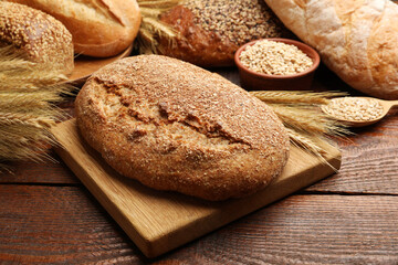Naklejka premium Loaves of fresh bread, grains and wheat spikes on wooden table, closeup