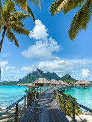 Turquoise lagoon, tropical overwater bungalows, lush palm trees, and Mount Otemanu view in Bora Bora, French Polynesia.
