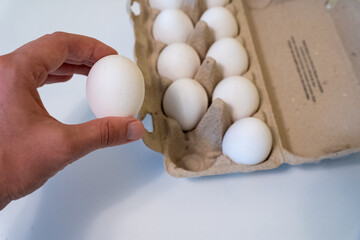 Hand picking a fresh white egg from carton