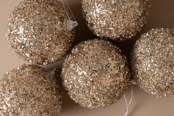 Christmas golden shiny baubles on beige background. Xmas greeting card. New Year concept. Mocha Mousse. Top view