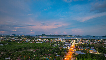 Aerial hyper lapse view of A breathtaking sunset paints the sky in vivid hues of orange and blue over a coastal town, with lush green hills framing the scene. cloud in dramatic sunset over the ocean