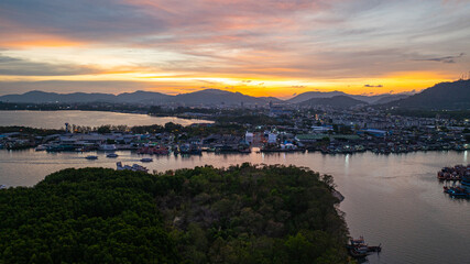 Aerial view of Stunning sunset featuring fishing port in Phuket. The vibrant sky transitions from soft purples to fiery orange hues, creating a tranquil and picturesque atmosphere.