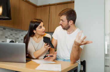 Obraz premium Couple checking bills at home with calculator and laptop, managing family finances and expenses together