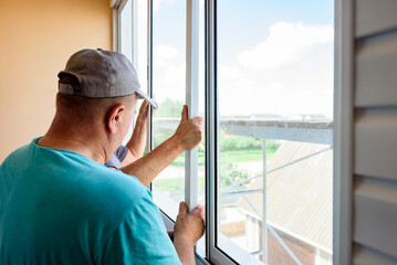 Installing metal-plastic window on a balcony in a house.