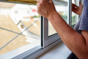 Installing metal-plastic window on a balcony in a house.