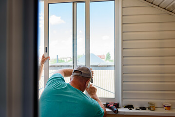 Masters repairing or installing metal-plastic window on a balcony in a house.