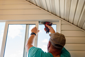 Masters repairing or installing metal-plastic window on a balcony in a house.