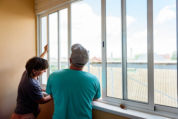 Masters repairing or installing metal-plastic window on a balcony in a house.