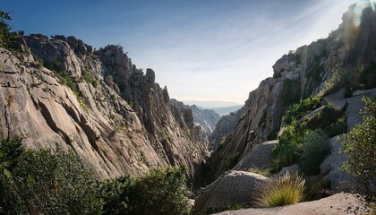 sheer granite cliffs sloping into shadowed gorge with subtle vegetation and dramatic geological formations