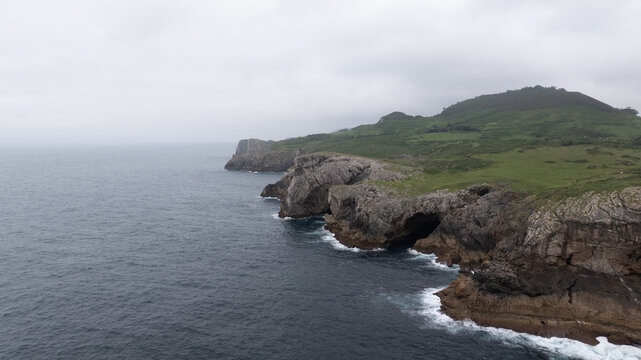 Dramatic cliffs and lush green hills meet the vast expanse of the Cantabrian sea along the rugged coastline of Asturias, Spain, creating a breathtaking vista