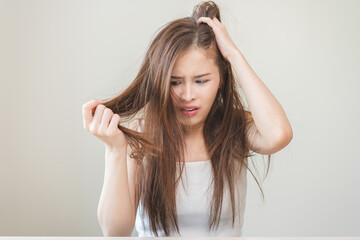 Damaged Hair, frustrated asian young woman, girl hand in holding splitting ends, messy unbrushed...