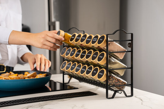 Young woman cooking in a modern kitchen with spices and fresh ingredients - Powered by Adobe