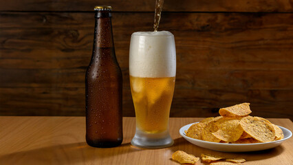Beer being served in a glass, with a bottle and crisps.