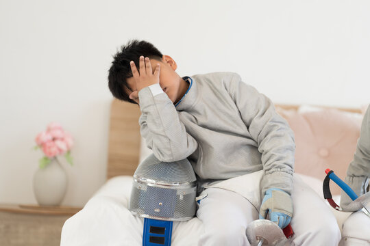Asian boy fencer train until exhausted during sitting on bed in gym - Powered by Adobe