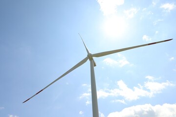 Modern wind turbine against blue sky, low angle view
