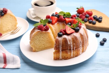 Pieces of delicious bundt cake with berries, glaze and mint on light blue wooden table, closeup