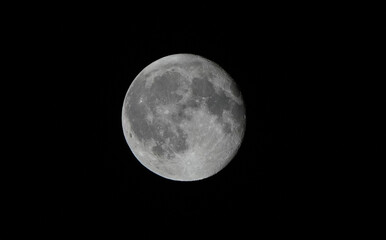 a detailed close-up of a full moon shining brightly at night in the dark sky