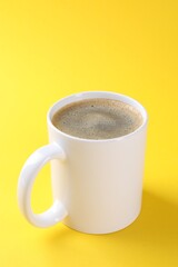 Aromatic coffee in cup on yellow background, closeup. Mockup for design