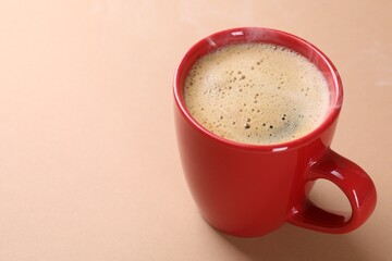 Aromatic coffee in cup on beige background, closeup. Space for text