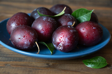 Ripe delicious blue plums in a plate. Fruit dessert. Selective focus.