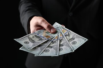 Man with dollar bills on black background, closeup