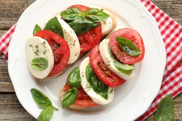 Delicious sandwiches with mozzarella cheese, tomatoes and basil on wooden table, top view
