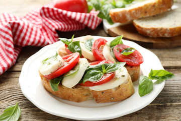 Delicious sandwiches with mozzarella cheese, tomatoes and basil on wooden table, closeup