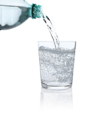Pouring refreshing soda water from bottle into glass on white background