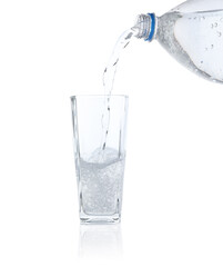Pouring refreshing soda water from bottle into glass on white background
