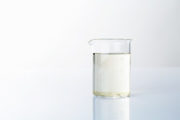 Glass beaker with dirty water on mirror surface, space for text
