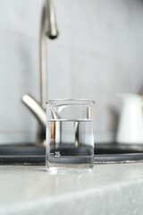 Beaker with clean water near sink on counter in kitchen, closeup